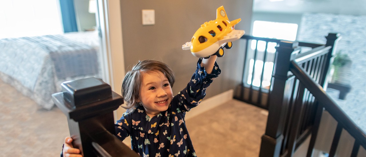 Girl Flying Toy Airplane in House